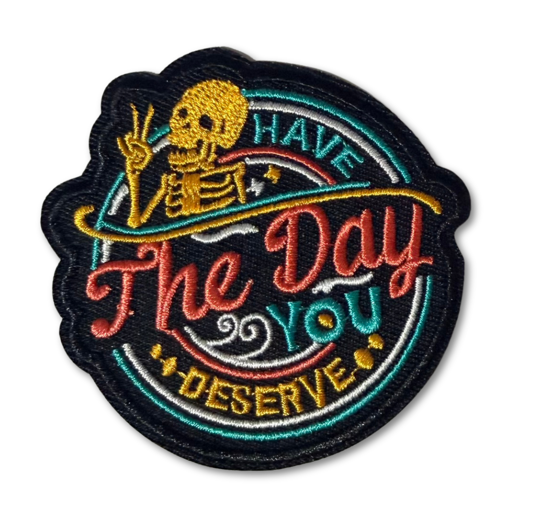 High Desert Hats embroidered patch with the phrase "Have The Day You Deserve" featuring colorful stitching and detailed design.
