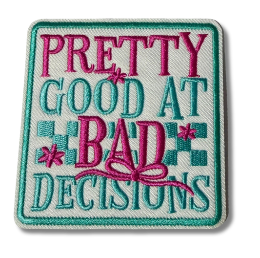 Embroidered patch with "Pretty Good at Bad Decisions" text by High Desert Hats, featuring colorful thread design on fabric background.