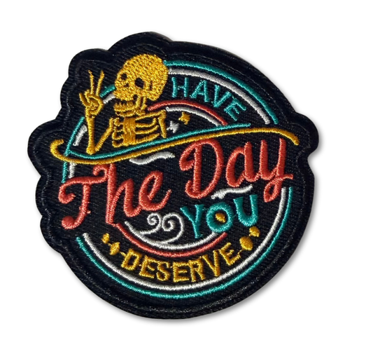 High Desert Hats embroidered patch with the phrase "Have The Day You Deserve" featuring colorful stitching and detailed design.