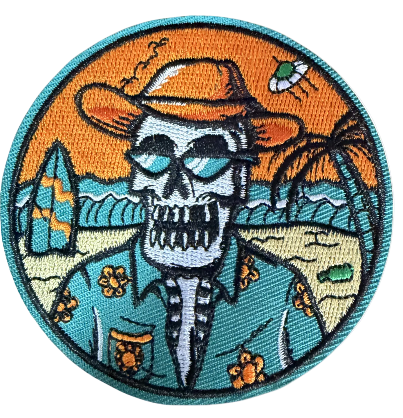 Circular patch with skull in cowboy hat at beach with surfboards and palm trees at sunset