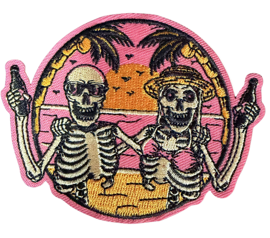 Two skeletons toasting bottles on a pink sunset beach with palm trees patch