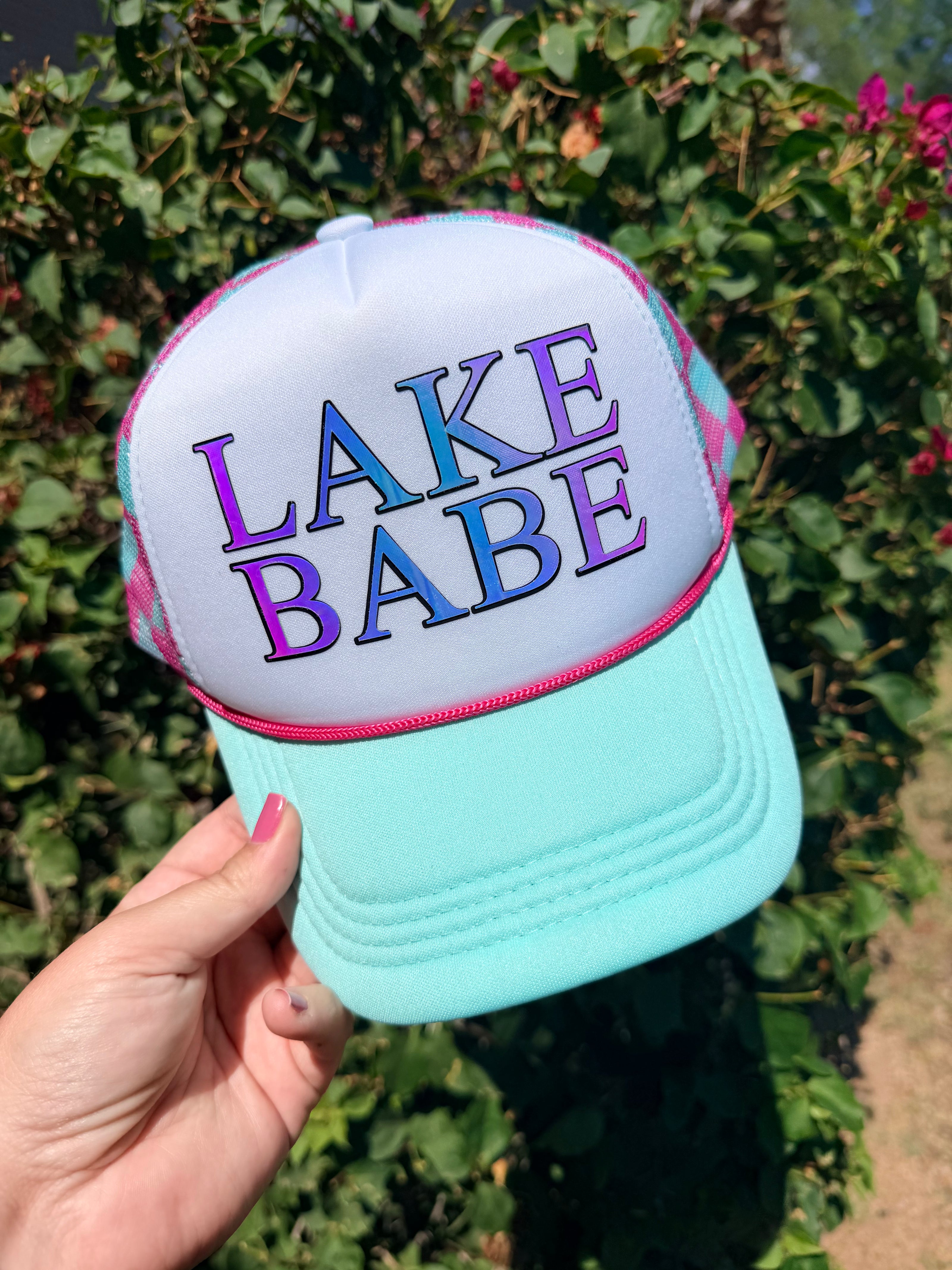 High Desert Hats Lake/River Babe trucker hat with white foam front, holographic graphic, and pink checker snapback.